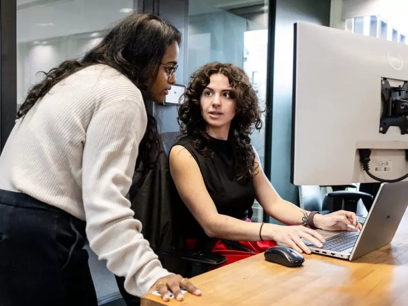 Two women discussing work on monitor