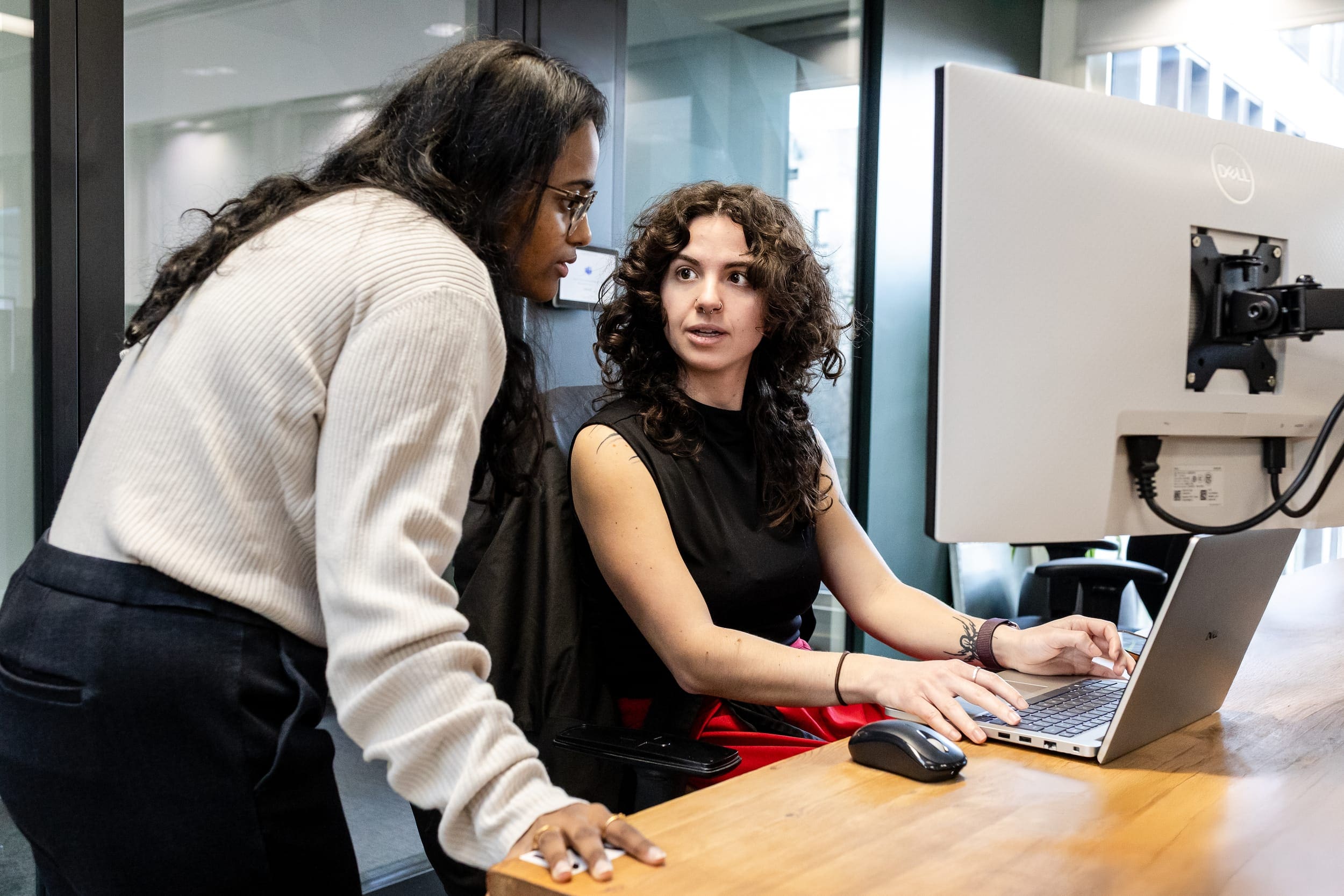 Two women discussing work on monitor
