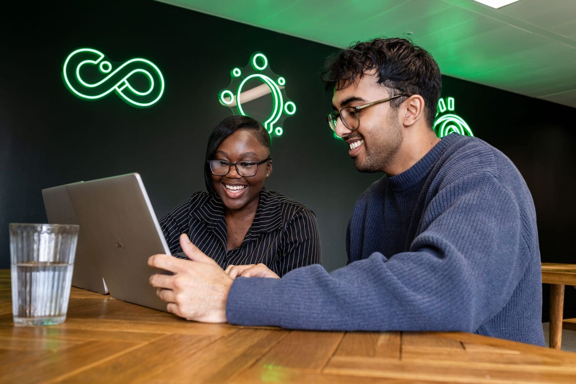 Man and woman smiling whilst working on laptops