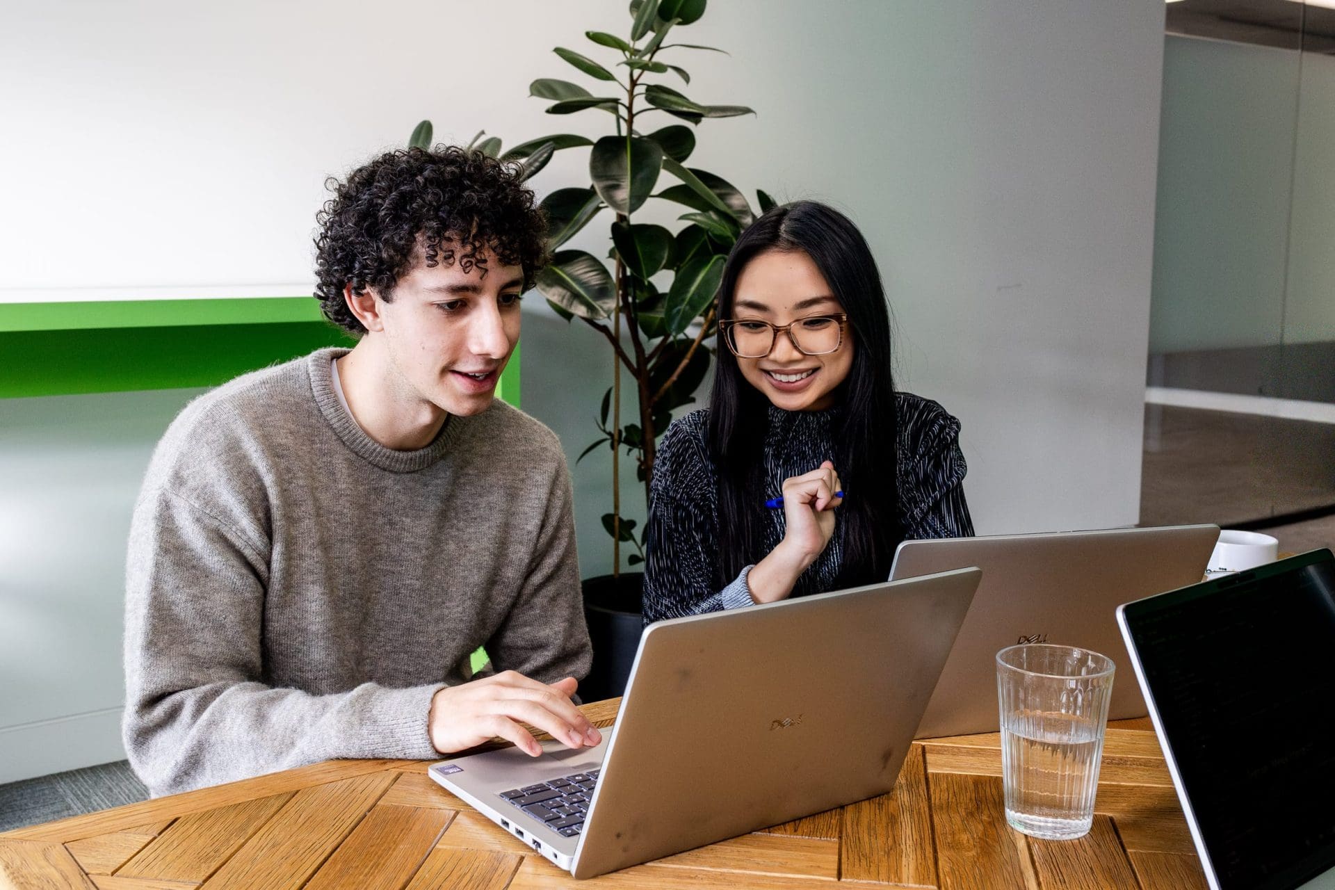Man and woman working on laptops in communal space